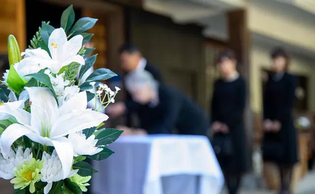 町田市家族葬 東横メモリアルの家族葬で白い花と参列者が並ぶ式場の様子