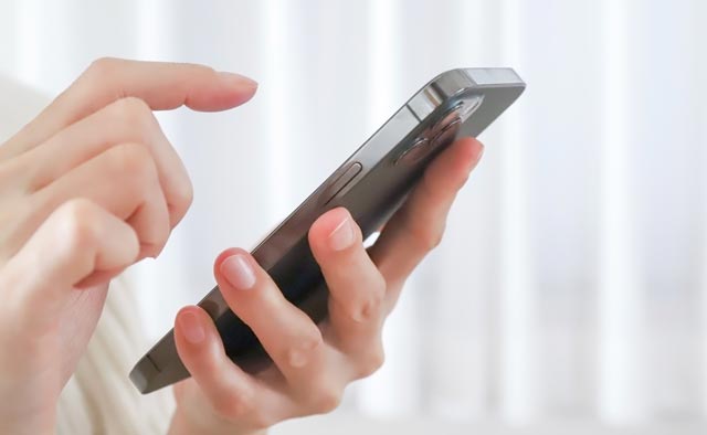 町田市家族葬 東横メモリアルへ電話で相談する手元のスマートフォンと発信準備する指