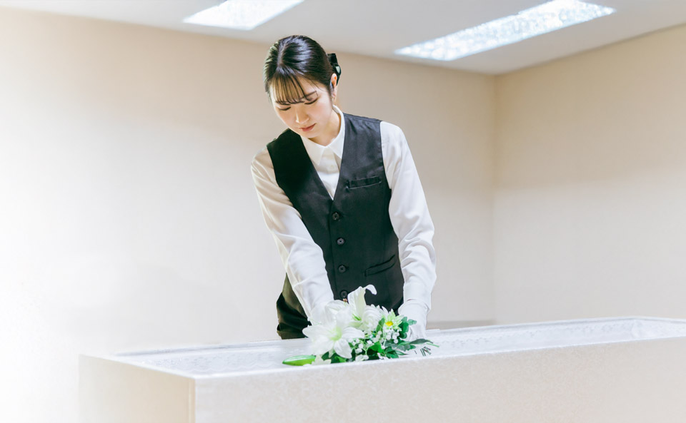 町田市家族葬 東横メモリアルのスタッフが白い花を棺に丁寧に飾る場面