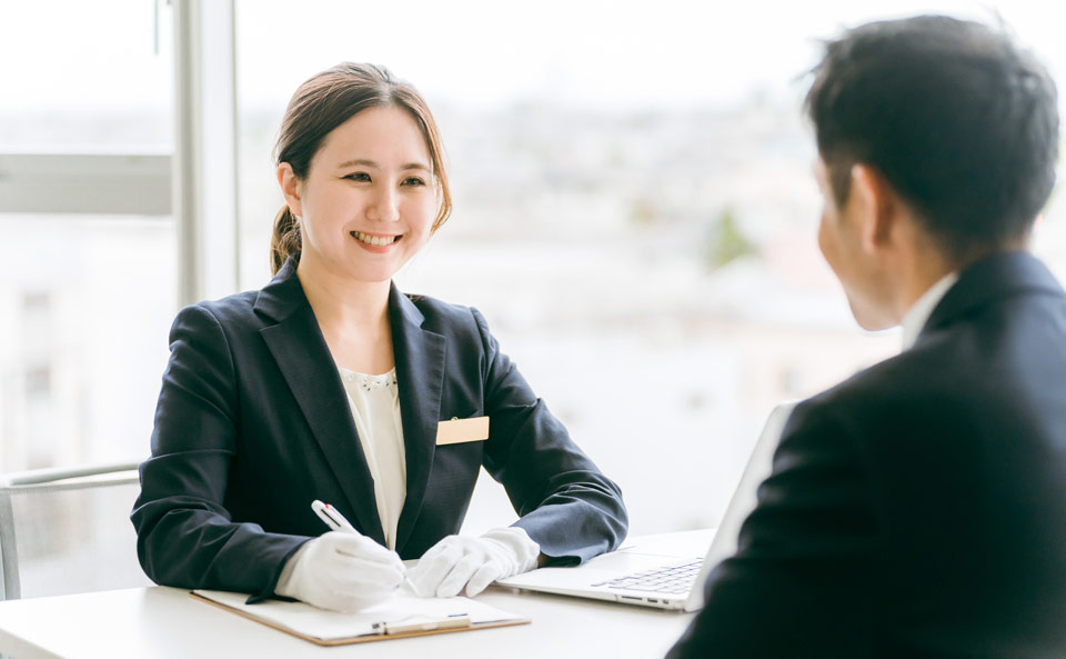 町田市家族葬 東横メモリアルのスタッフが搬送相談で笑顔で受付する様子、町田市　葬儀社